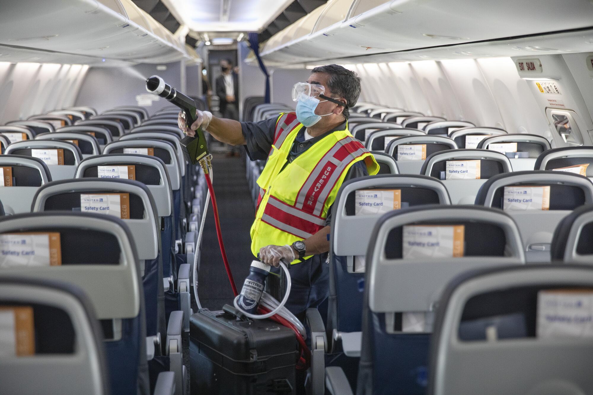 Jose Mendoza uses an electrostatic sprayer to disinfect the cabin of a United Airlines 737 jet on July 9 at LAX.