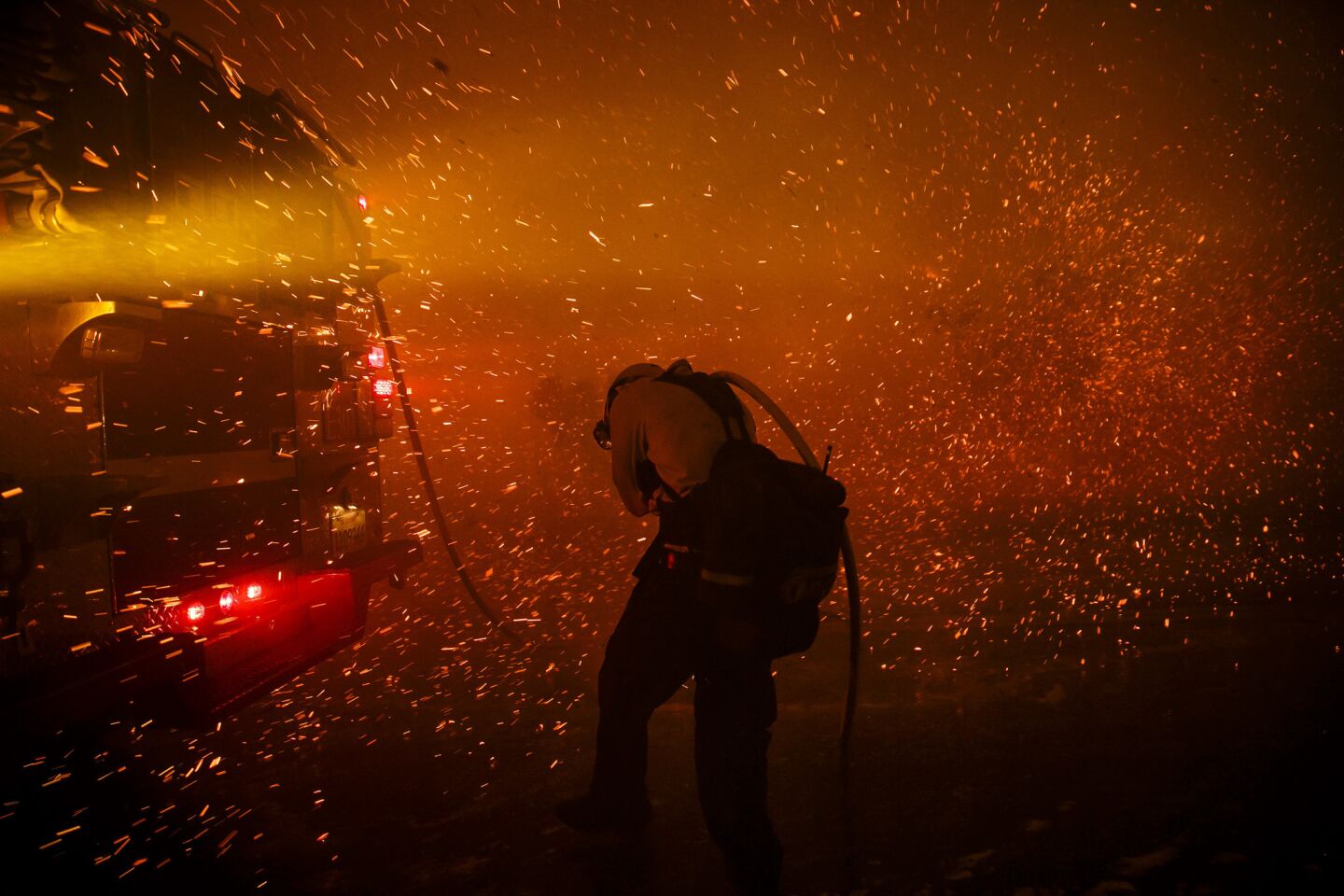 A firefighter ducks as the wind changes direction and blows ember towards their direction, at the Sherpa Fire in Goleta, Calif.