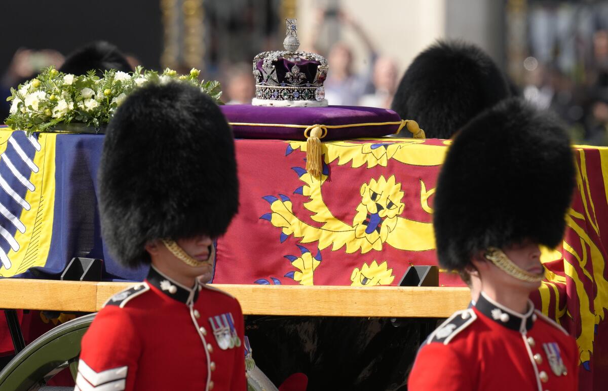 Varias personas esperan antes del paso del cortejo fúnebre de la reina Isabel II desde el Palacio de Buckingham a Westminster