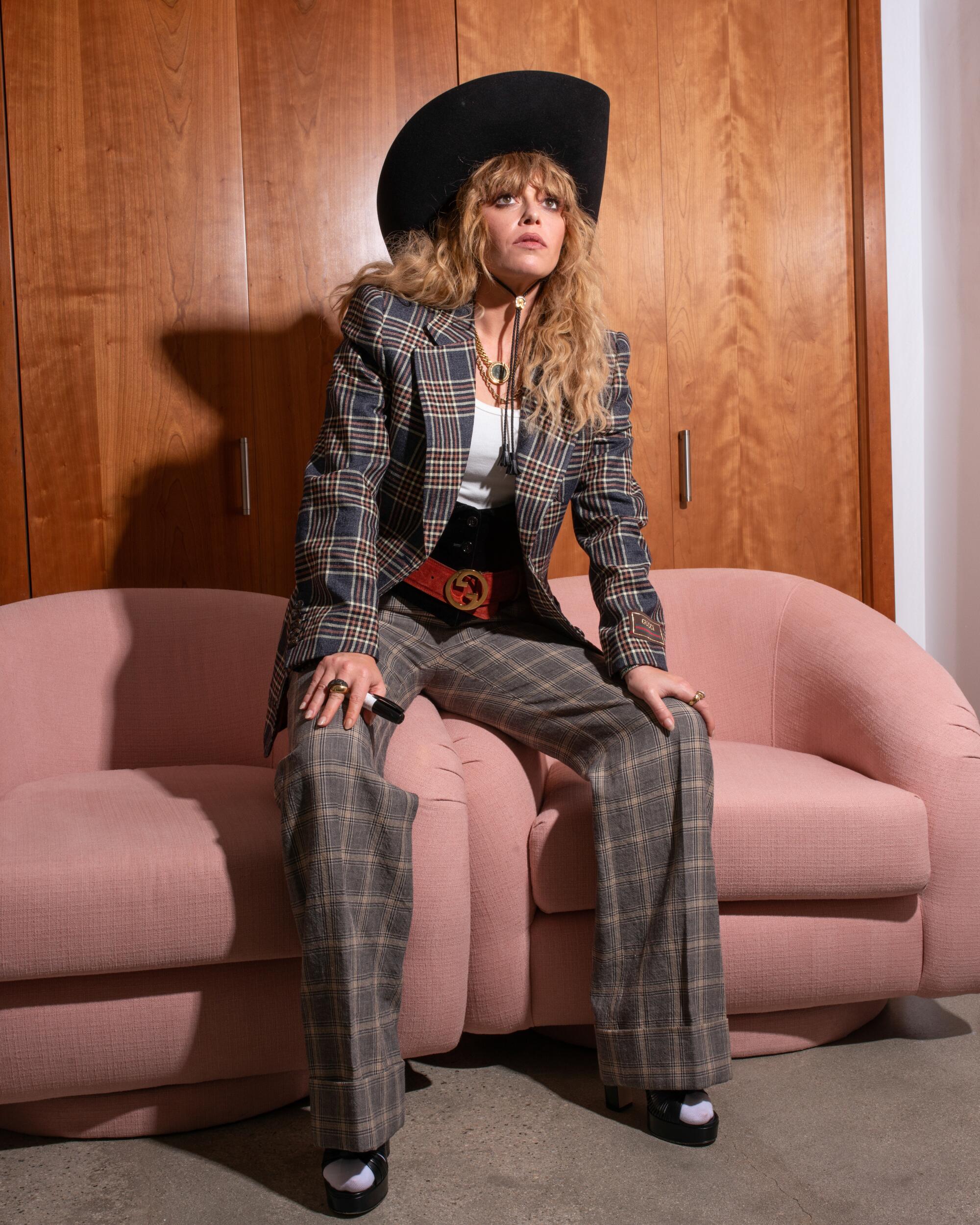 A woman sits on the arm rests of two pink chairs pushed together