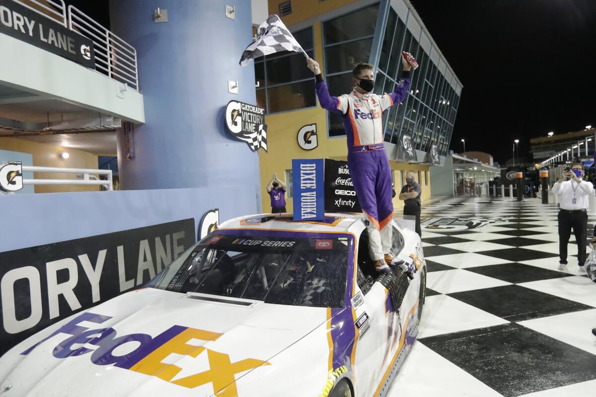 Denny Hamlin celebrates while standing on his car after winning a NASCAR Cup race at Homestead-Miami Speedway.