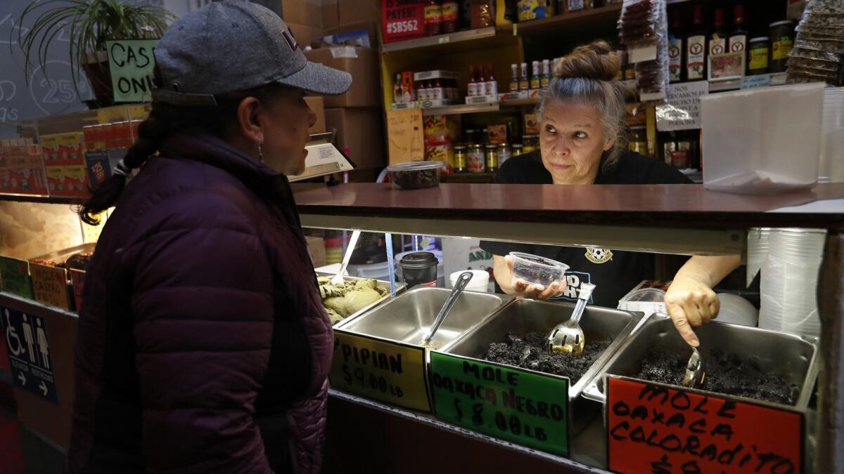 Sonia Solas, left, orders a container of mole from vendor Rocio Lopez inside the Grand Central Market.