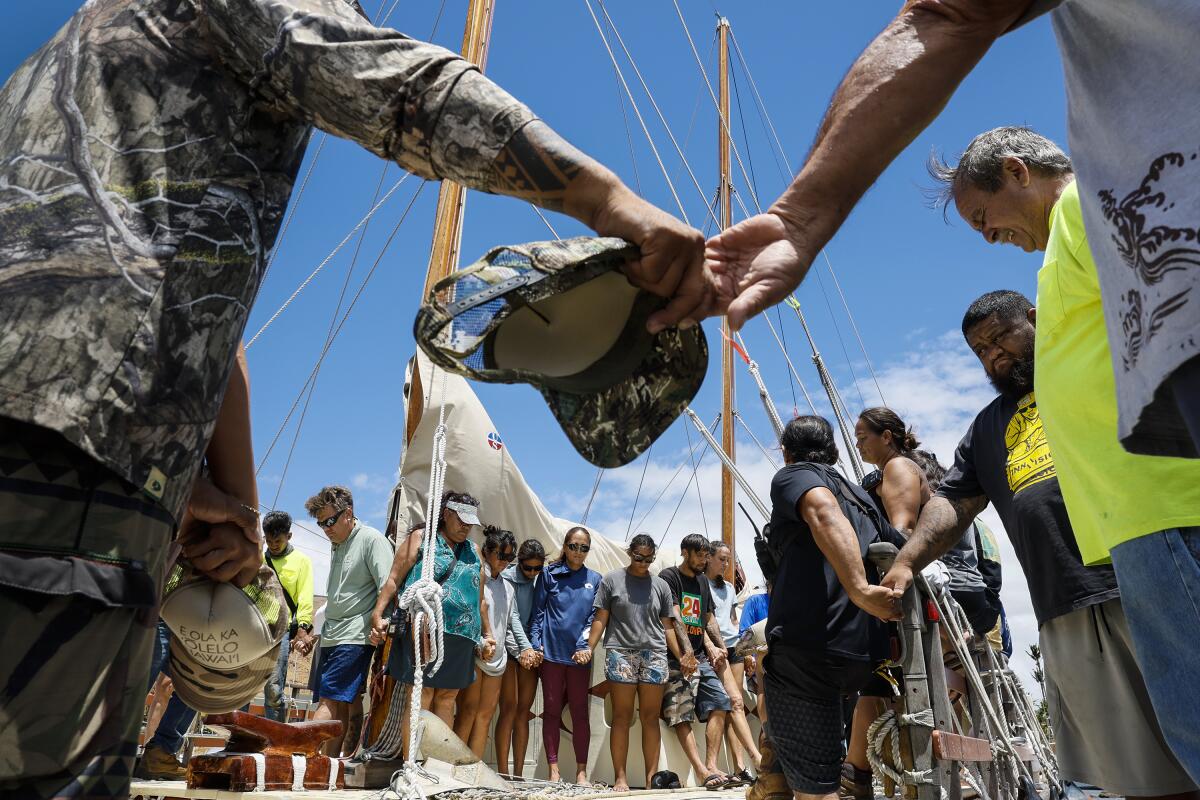 Hawaiians join hands in prayer after delivering a boat load of supplies for Lahaina fire victims at Maalaea Harbor, Maui.
