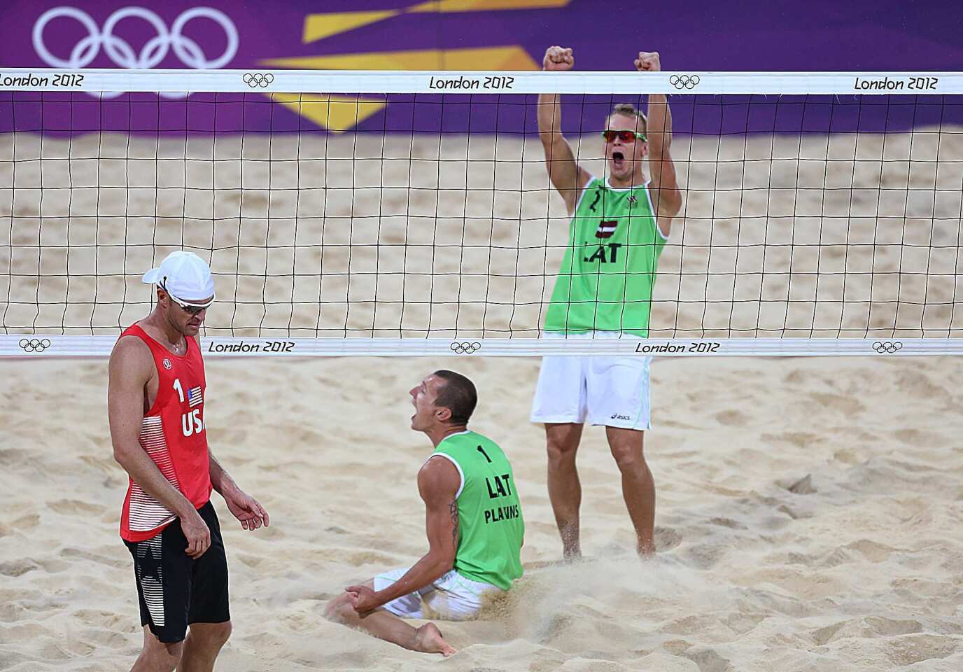 Jacob Gibb of the United States looks away as he and teammate Sean Rosenthal fall to Martins Plavins, center, and Janis Smediins of Latvia in the men's beach volleyball quarterfinals, 2-1.