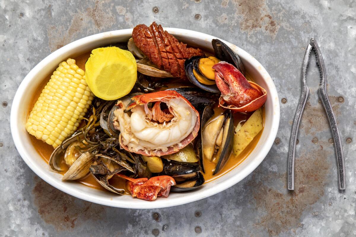 A bowl of seafood, corn on the cob and lemon