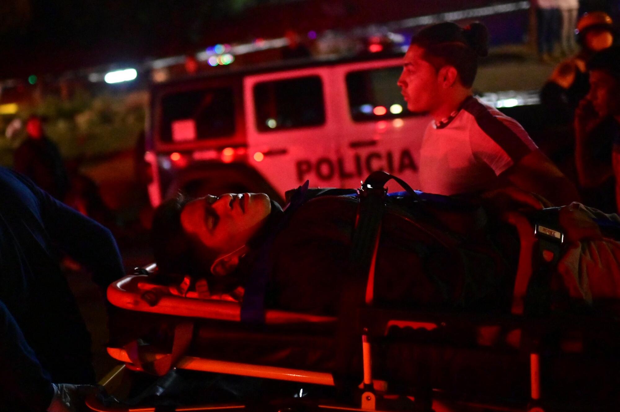 An injured person on a stretcher bathed in red light at night.