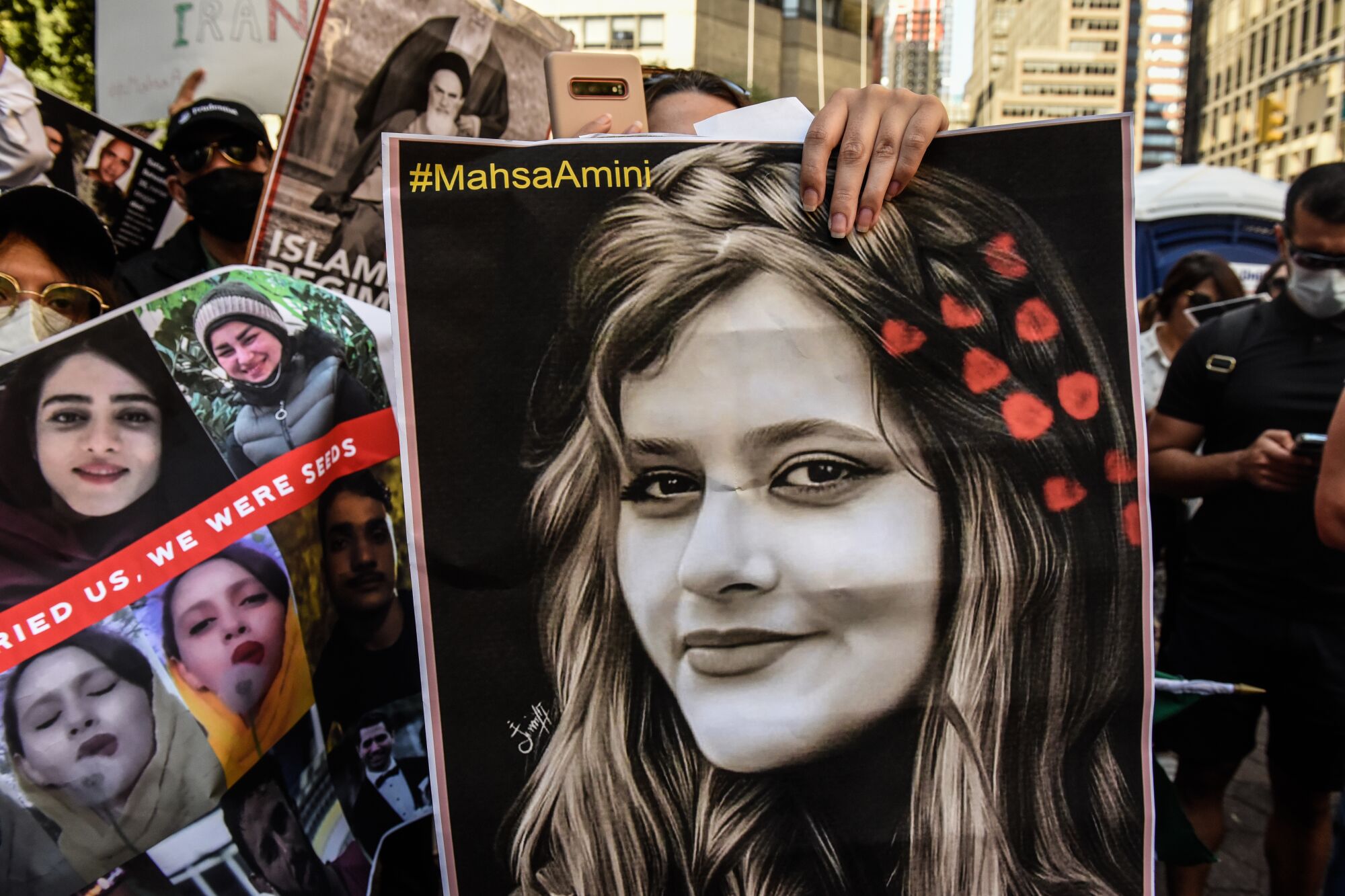 Posters held by protesters show 22-year-old Iranian woman Mahsa Amini
