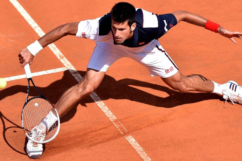 Novak Djokovic slides into a volley during his three-set victory over Milos Raonic in a semifinal of the Italian Open on Saturday.