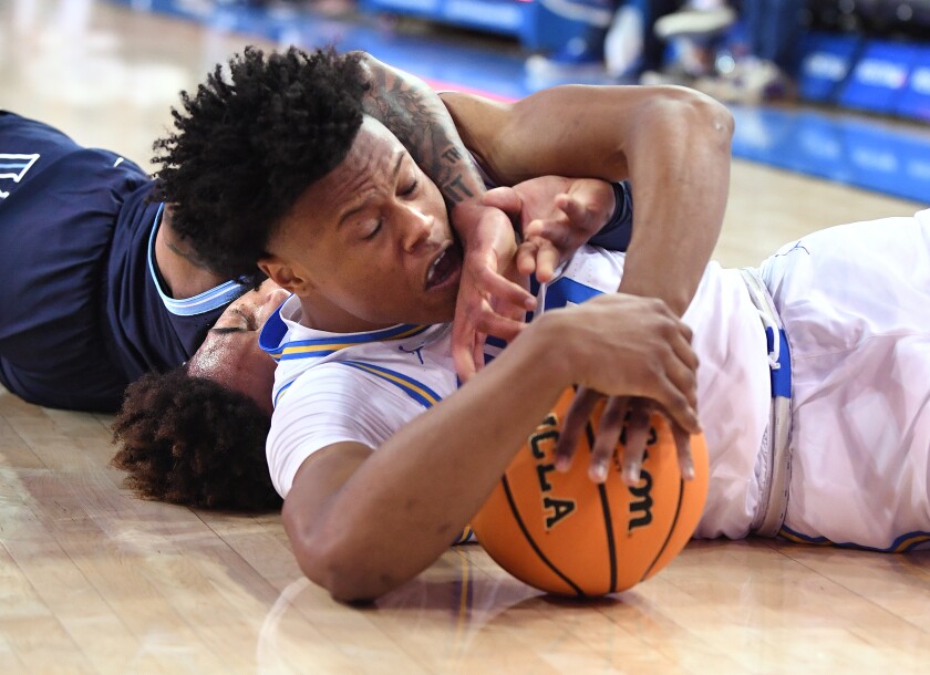 Jaylen Clarke of the University of California, Los Angeles battles for a free ball in the first half with Justin Moore of Villanova.