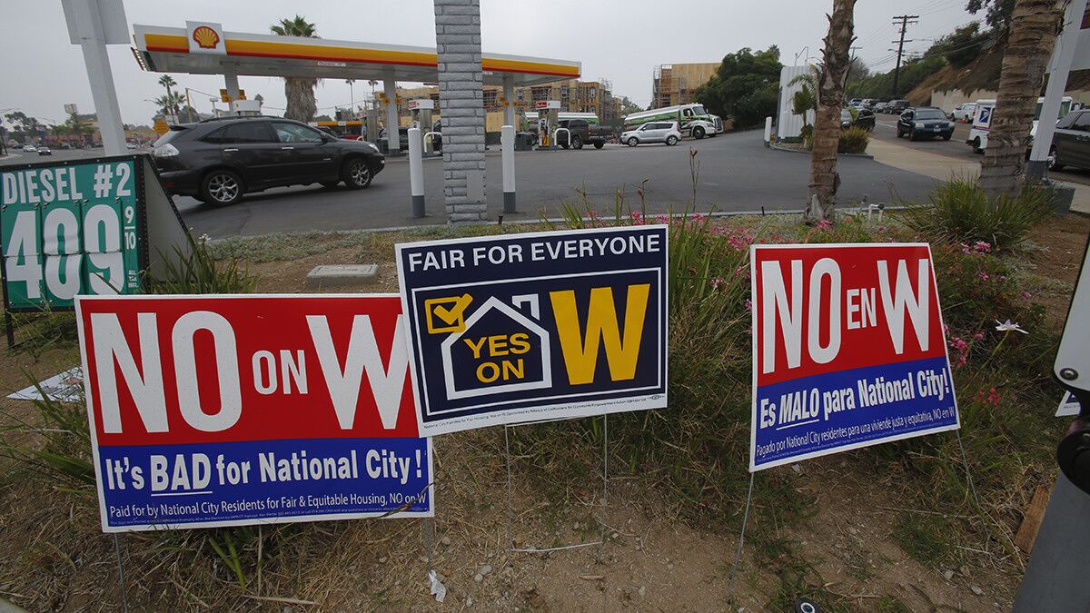 Election signs supporting and opposing Measure W, a rent control measure on the November ballot, on the corner of Palm Avenue and Plaza Blvd where a 77-unit apartment building is under construction.