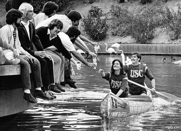 Chuck Howard and Debbie Debrauwere of USC in a 72-hour canoe race at Busch Gardens in Van Nuys are given beer by spectators. Feb. 17, 1975.