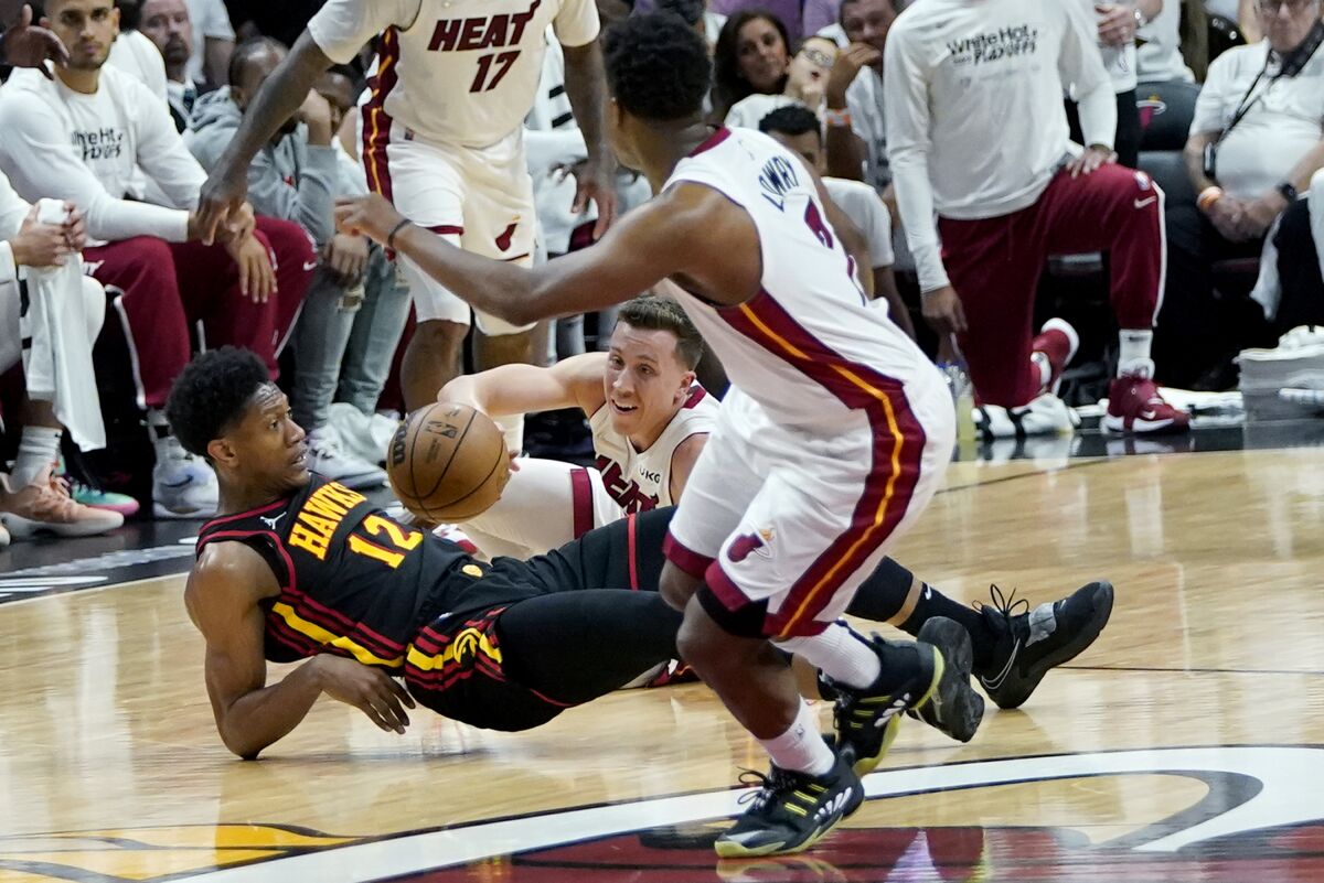 Atlanta Hawks forward De'Andre Hunter (12) and Miami Heat guard Duncan Robinson go for a loose ball during the first half of Game 1 of an NBA basketball first-round playoff series, Sunday, April 17, 2022, in Miami. (AP Photo/Lynne Sladky)