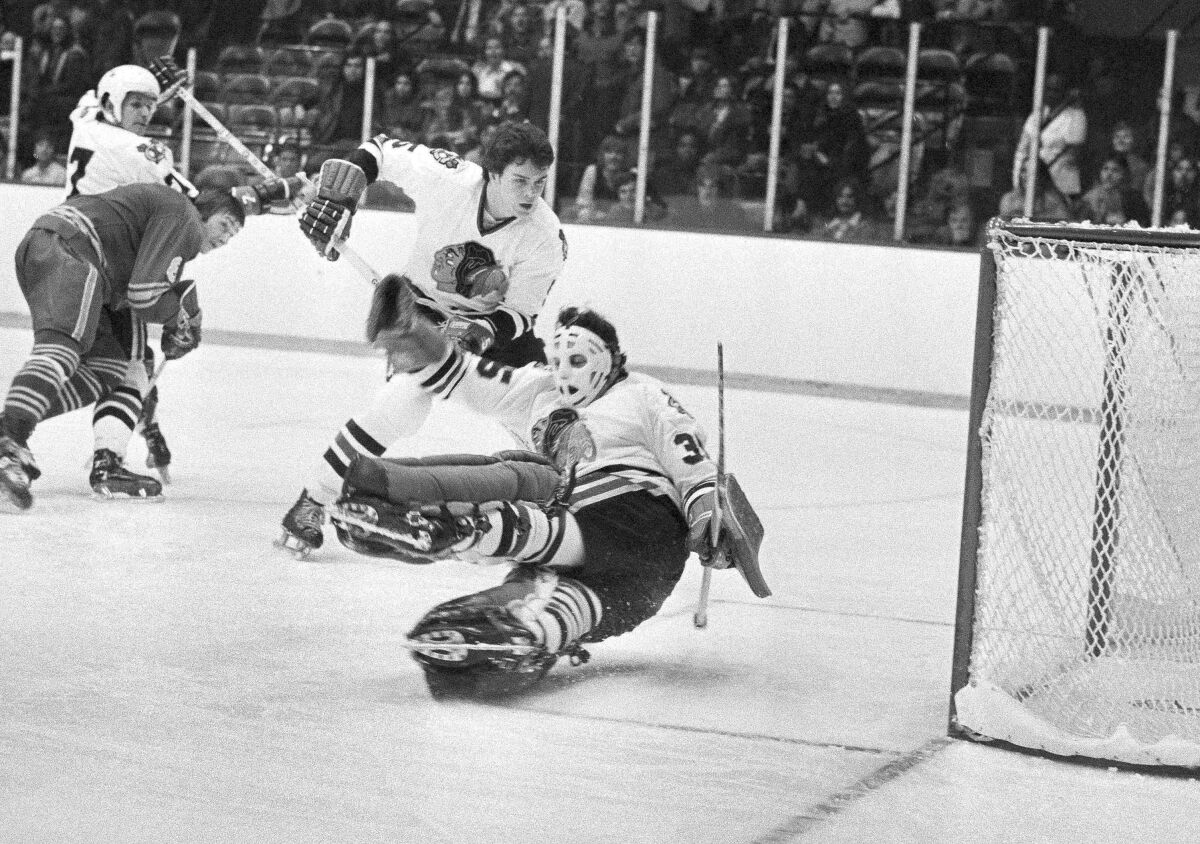 FILE - In this Dec. 19, 1973, file photo, Chicago Blackhawks goalie Tony Esposito (35) stops a Buffalo Sabres shot during the first period of an NHL hockey game in Chicago. Chicago's Phil Russell (5) watches as Buffalo's Jim Lorentz (8) keeps Chicago's Pit Martin (7) out of the play. Esposito, a Hall of Fame goaltender who played almost his entire 16-year career with the Blackhawks, has died following a brief battle with pancreatic cancer, the team announced Tuesday, Aug. 10, 2021. He was 78. (AP Photo/Fred Jewell. File)