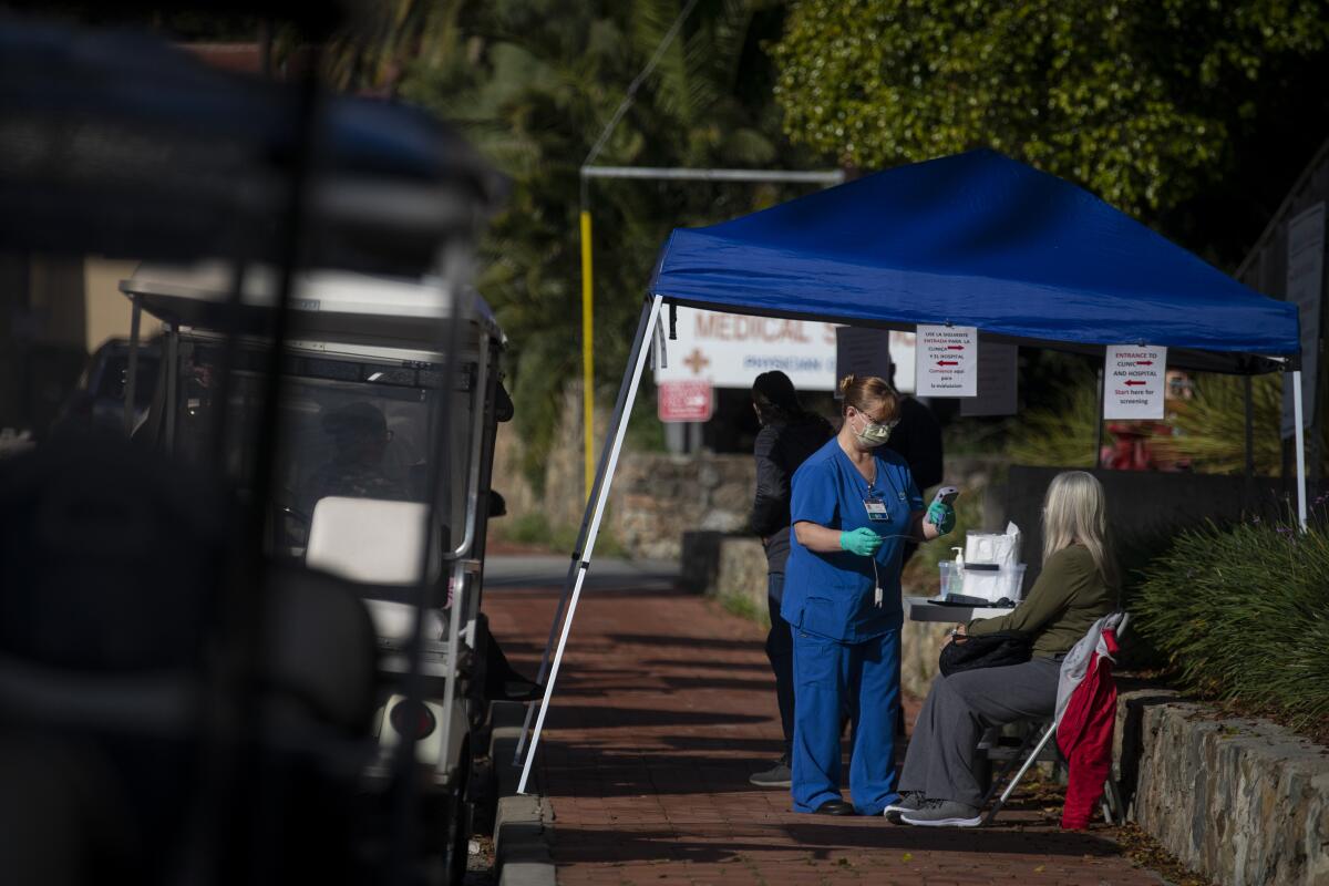 A nurse takes the vital signs of a woman in a medical tent outside a hospital.