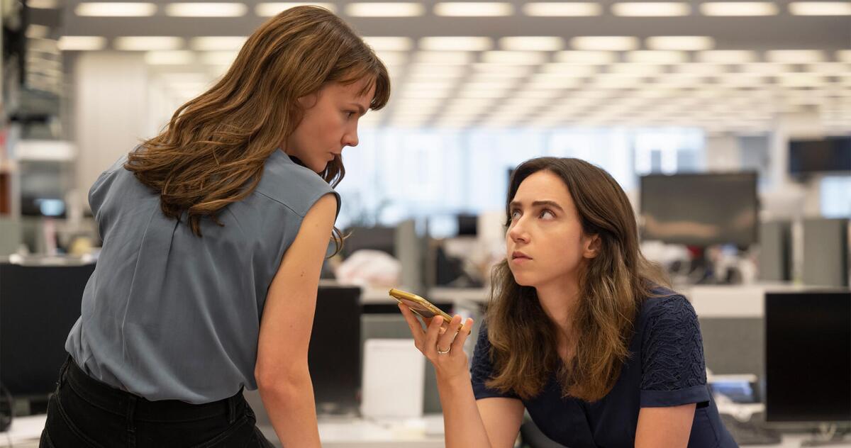 Two  women in a newsroom listen to a phone recording.