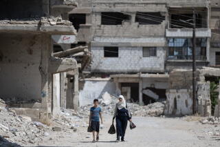 A mother and her child walk down one of the destroyed streets in Yarmouk, the once vibrant Palestinian camp outside Damascus.