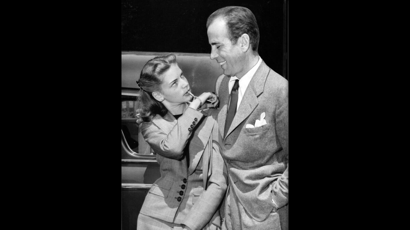 Lauren Bacall and Humphrey Bogart at Union Station upon their return to California following their wedding in Ohio. Bacall is blowing on a small whistle attached to her bracelet.