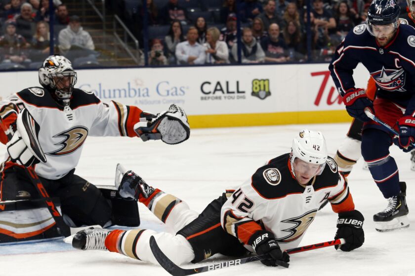 Anaheim Ducks defenseman Josh Manson, center, tries to control the puck in front of Ducks goalie Ryan Miller, left, and Columbus Blue Jackets forward Nick Foligno during the second period of an NHL hockey game in Columbus, Ohio, Friday, Oct. 11, 2019. (AP Photo/Paul Vernon)