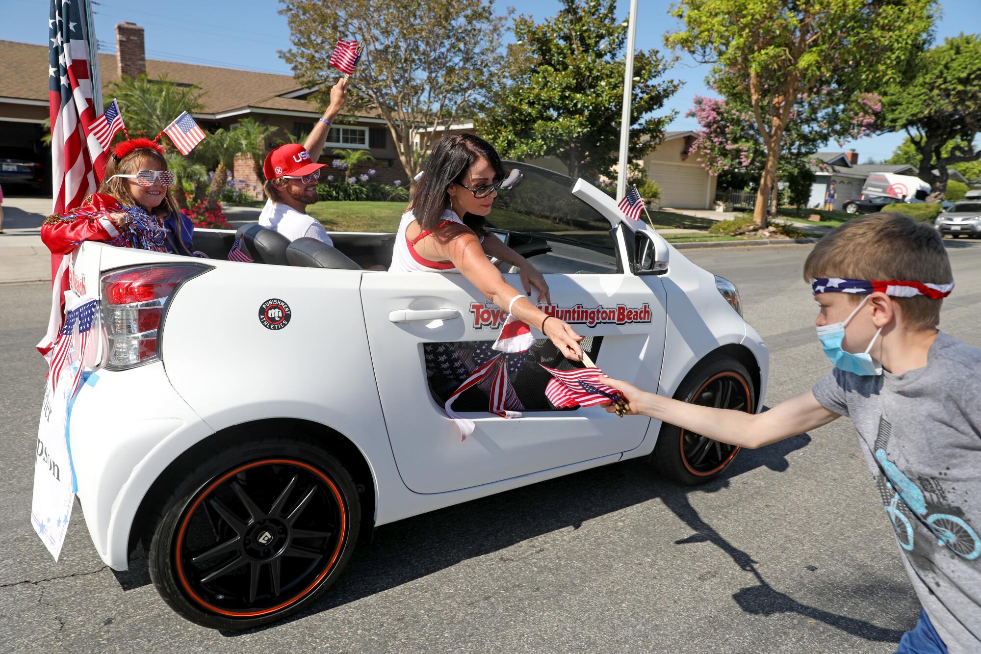  Participants hand out flags to Ezekiel Schmidgall, of Washington D.C., in the OneHB Neighborhood Parade