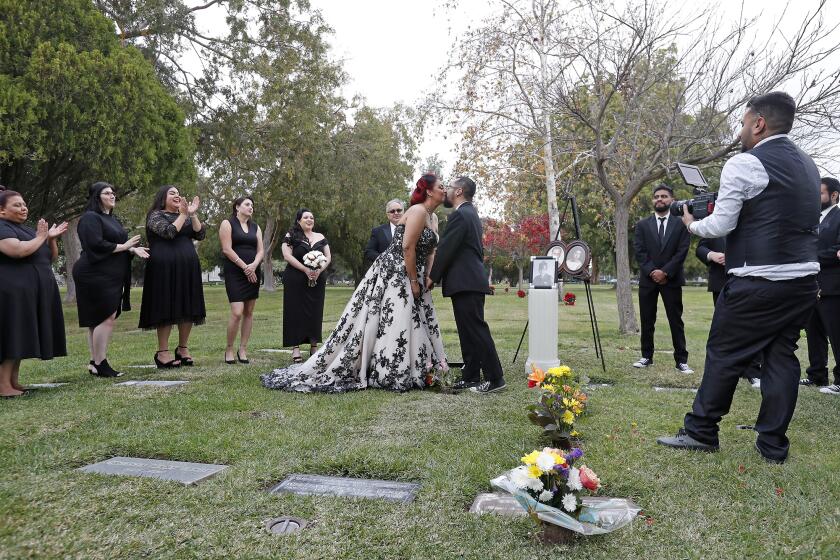 Sabrina Gandara, 34, and Andrew Rodriguez, 32, kiss as wife and husband as they stand beside SabrinaÕs beloved grandpa, Joe GandaraÕs grave at Fairhaven Memorial Park and Mortuary Saturday afternoon.