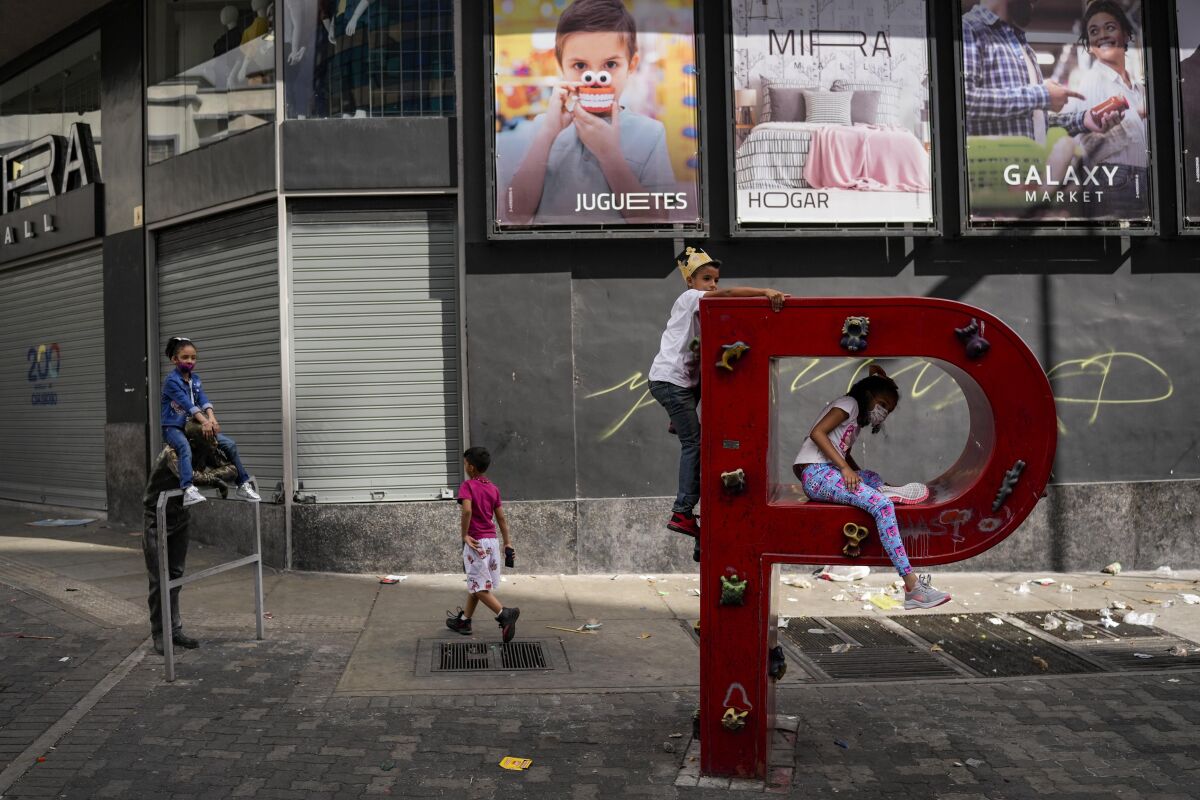 FILE - Children play on the letter "P" that is part of the acronym for the state-run oil company Petroleos de Venezuela S.A. (PDVSA) on the sidewalk in Caracas, Venezuela, Jan. 2, 2022. The United States government is moving to ease a few economic sanctions on Venezuela, which sits atop the world’s largest oil reserves and where about three quarters of its population live on less than $1.90 a day and lack access to clean, running water and electricity. (AP Photo/Matias Delacroix, File)