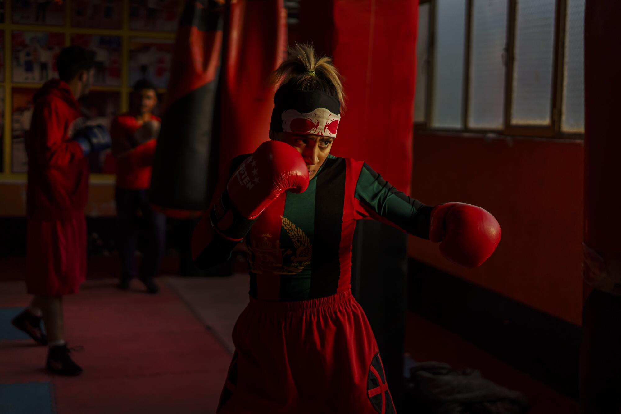 Khurshid Muhammadi, in boxing gloves, holds a fighting stance inside a Kabul gym.