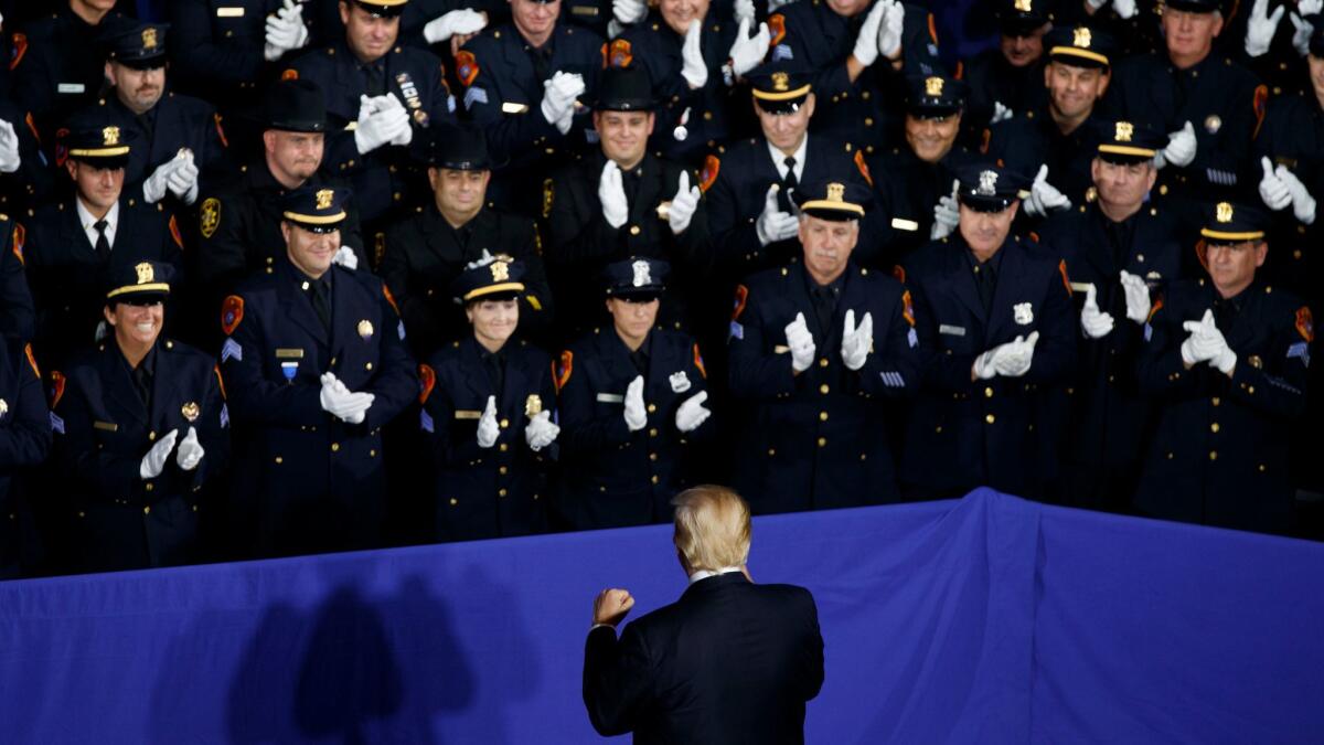 Law enforcement officers applaud President Trump on Friday as he arrives to deliver a speech about the street gang MS-13 in Brentwood, N.Y.
