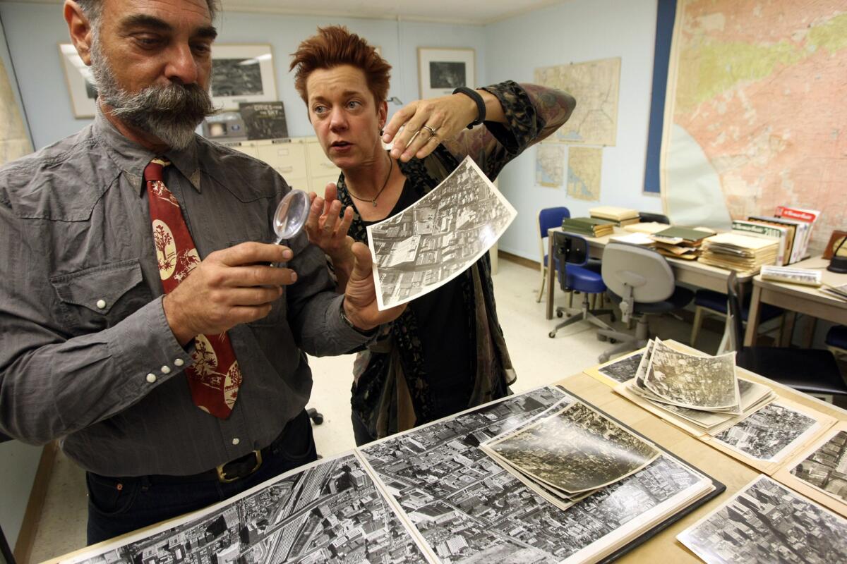 Professor Dydia DeLyser, right, and research partner Paul Greenstein look over a historic photograph that proves that the nation's first neon billboard wasn't erected in 1923 at 7th and Flower in downtown L.A.