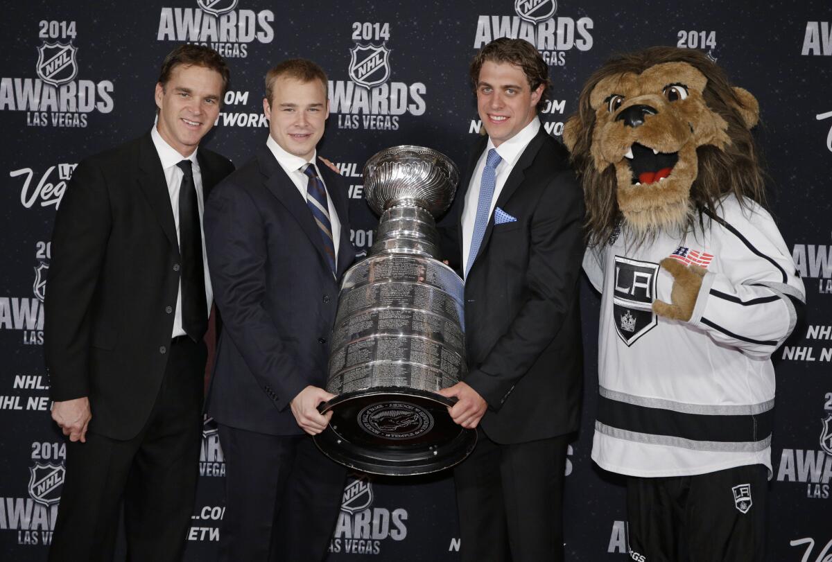 Kings executive Luc Robitaille, left, and players Dustin Brown and Anze Kopitar pose with the Stanley Cup on June 24.