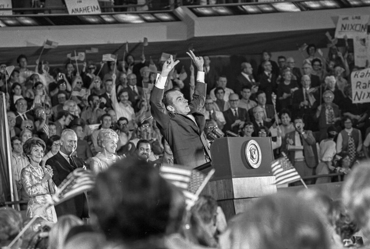 Oct. 30, 1970: President Nixon raises his arms in a V for victory gesture as he addresses a rally at the Anaheim Convention Center. Also on the platform is Nancy Reagan, at left.