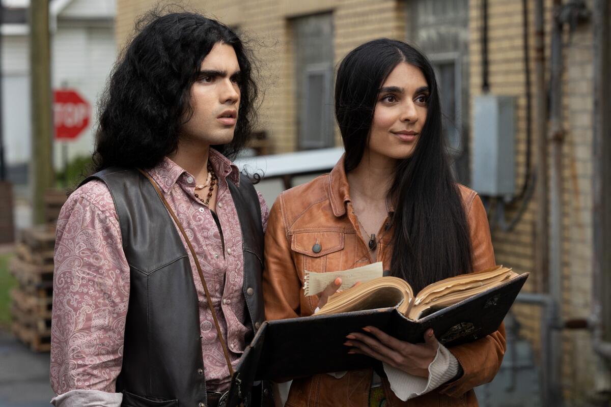 A man, left, and a woman look up while the woman holds a large, old book