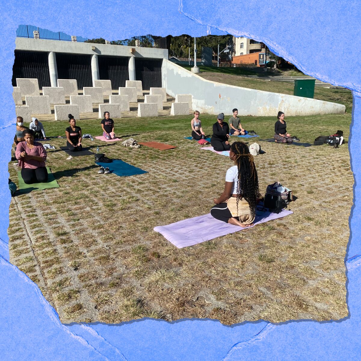 People sit outdoors on yoga mats.