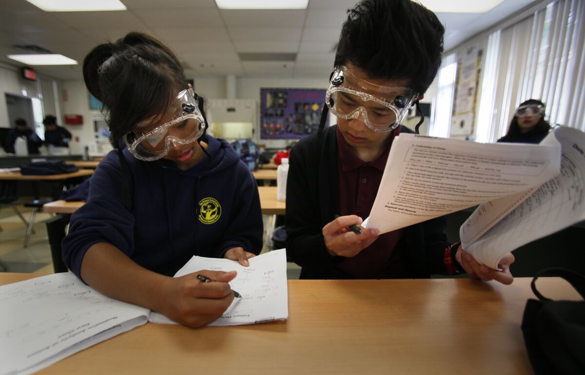 In an AP Chemistry class, Elayne Tram Nguyen, 18, left, and Destin Dao, 18, go over their notes for an experiment they were performing in class Tuesday morning.