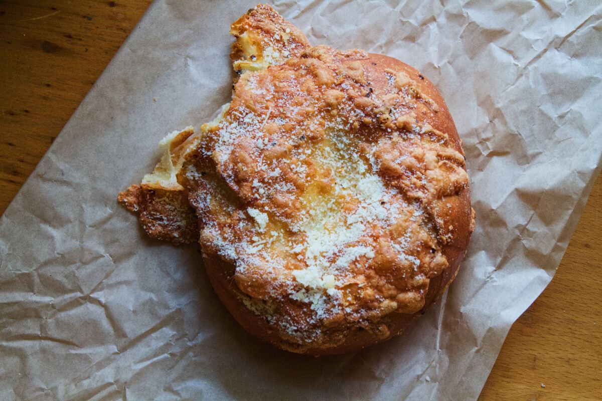 A bagel is stopped with crispy cheese and Parmesan, with pepper studded throughout.