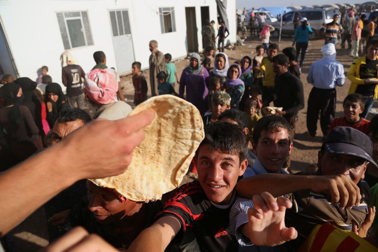 Yazidis gather for food at the Nowruz camp in Derike, Syria. The Iraqi refugees have new heroes: Kurdish fighters who battled militants to carve an escape route for tens of thousands trapped on a mountaintop.