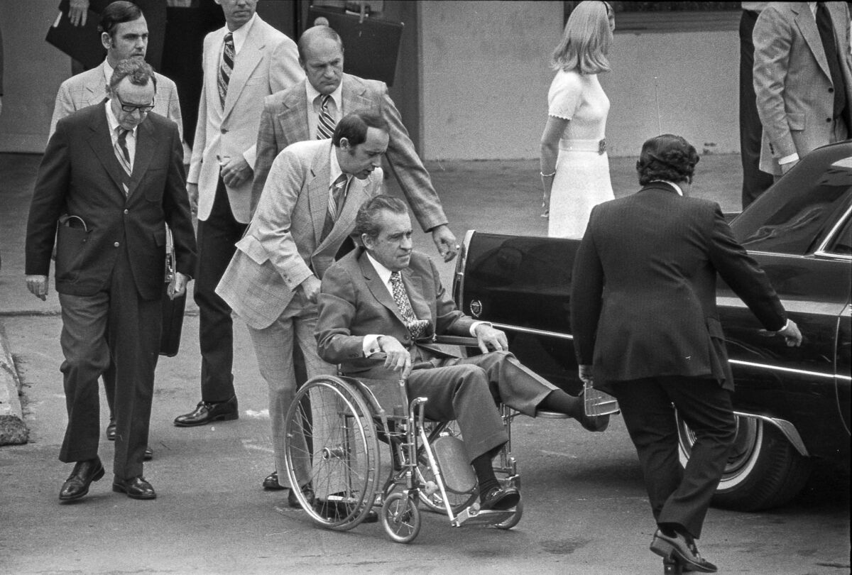 Oct. 4, 1974: Secret Service agents, aides and hospital personnel help former President Nixon into limousine for departure from a Long Beach hospital.