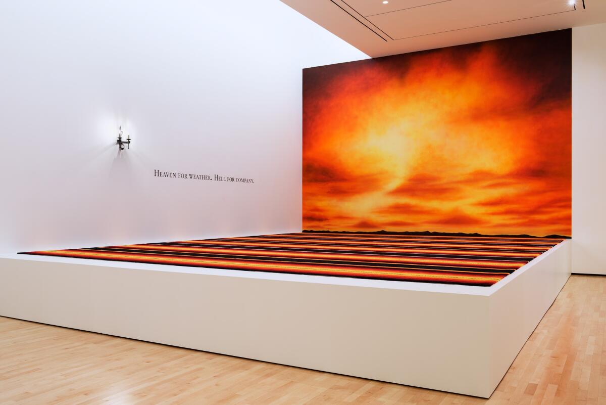 In Alexis Smith's "Red Carpet," a rug leads to a wall mural depicting either a glorious sunset or a wildfire inferno.