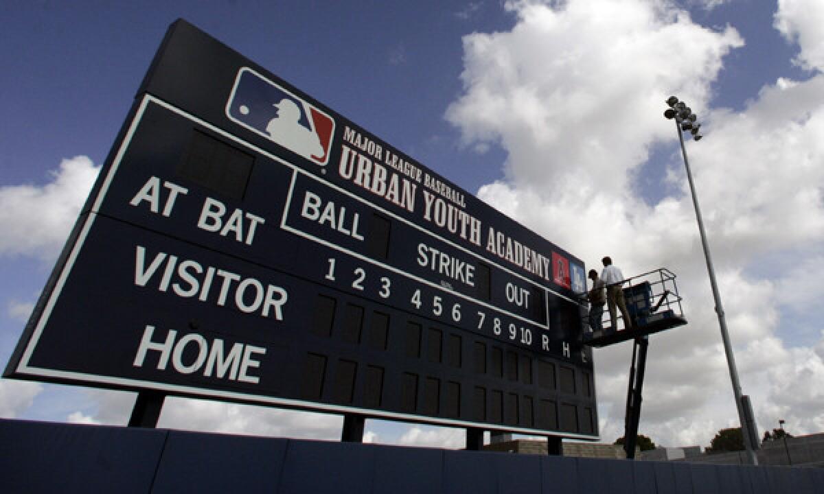 Workers put the finishing touches on a scoreboard at the MLB Youth Academy in Compton.