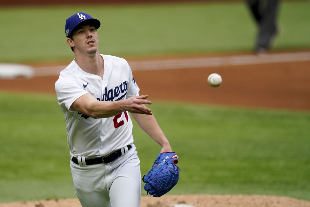 Dodgers pitcher Walker Buehler tosses the ball to first base to record the final out of the fourth inning.