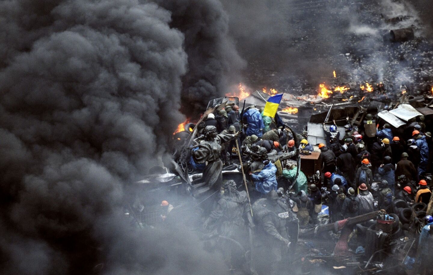Ukrainian protesters stand behind burning barricades during a face-off against police in Kiev.