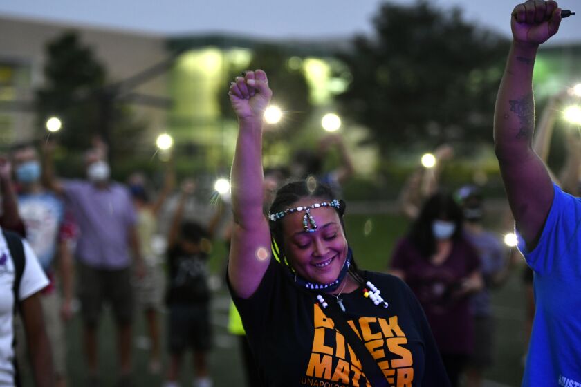 Ebony Wallace holds her fist in the air along with other participants at an event, Gathering in Gratitude presented by Motherhood, held to honor the memory of Elijah McClain, in Denver on Sunday, Aug. 23, 2020. McClain died after being stopped by police last year in the suburb of Aurora. (Helen H. Richardson/The Denver Post via AP)
