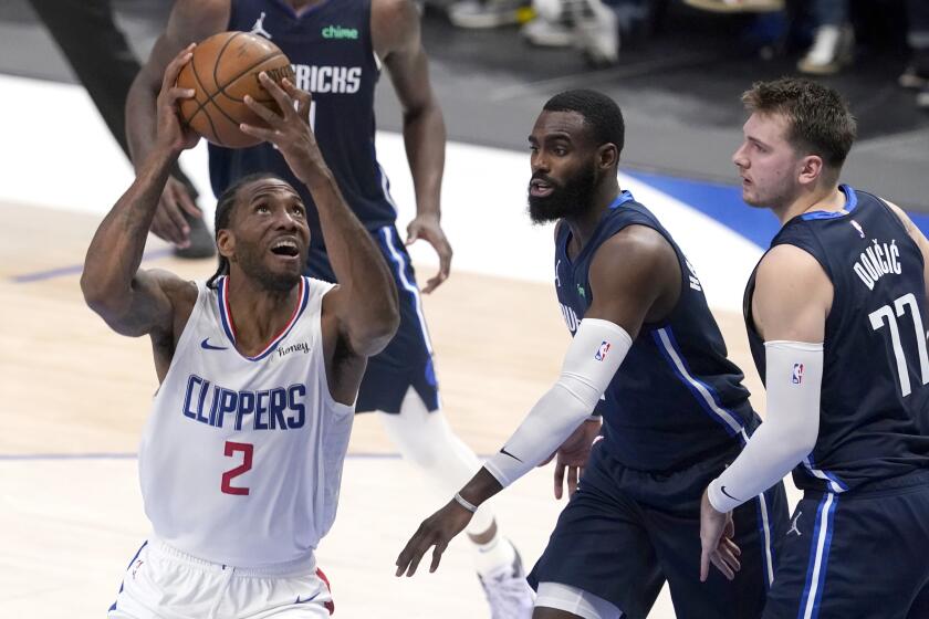 Clippers forward Kawhi Leonard drives for a layup against Dallas' Tim Hardaway Jr., center, and Luka Doncic.
