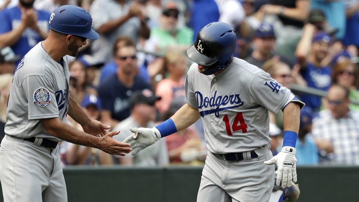 The Dodgers' Enrique Hernandez, right, is congratulated by third base coach Chris Woodward after homering in the sixth inning Sunday against the Seattle Mariners.