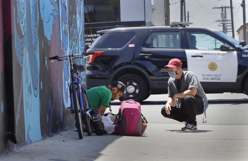 PATH outreach specialist Jessie Angeles check checks on homeless man Martin Pascua in City Heights.