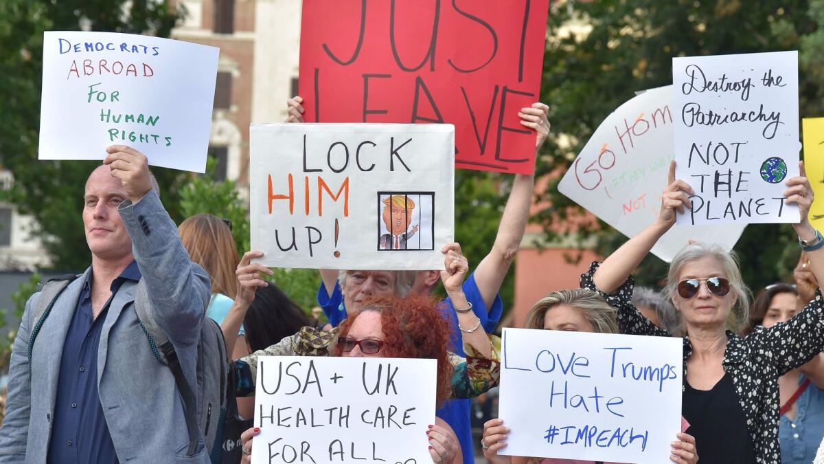 A small group of people in Rome hold posters protesting the visit of President Trump, on May 23, 2017.