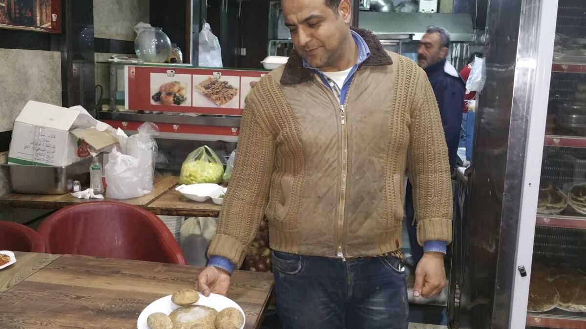 Saameh Kajaan shows off a plate of kibbeh at his restaurant Atayeb, where he and his brother serve Aleppan feasts every day.
