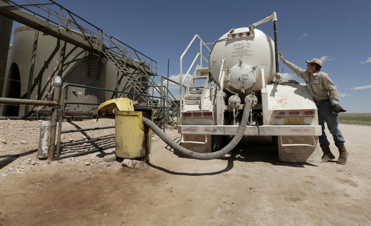 File - In this April 24, 2015, filephoto, a worker empties oilfield wastewater from a tank truck into storage tanks on Carl and Justin Johnson's ranch near Crossroads, N.M. Labor shortages, supply problems and volatile prices have made oil companies cautious about new drilling even as U.S. politicians push for increased production. (AP Photo/Charlie Riedel, File)
