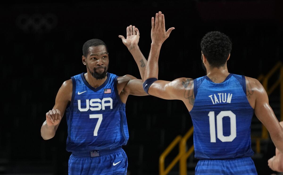 Basketball players Kevin Durant and Jayson Tatum exchange a high-five at the Tokyo Olympics.