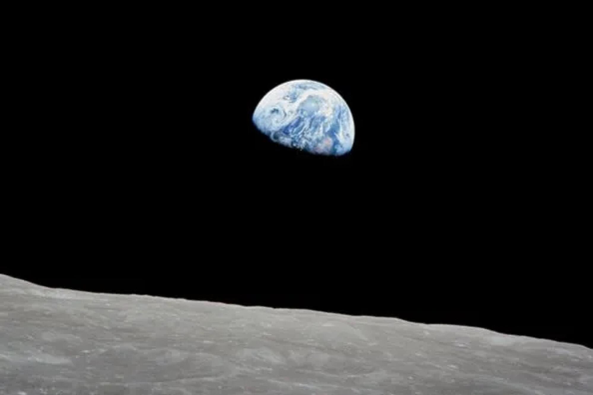Earth rises above the surface of the moon.