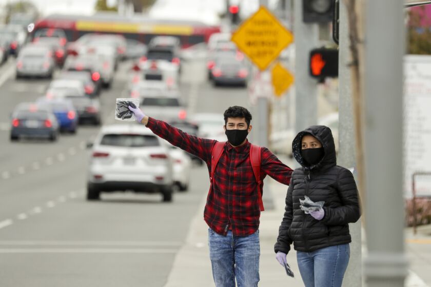 INGLEWOOD, CA - APRIL 10: Stuart Reyes, 19, left, and his 16-year-old sister Stephanie Reyes sell mask for $5 each at 3000 block of West Century Blvd. in Inglewood. Stuart said he is selling masks to support his mother in rent. Inglewood, CA. (Irfan Khan / Los Angeles Times)
